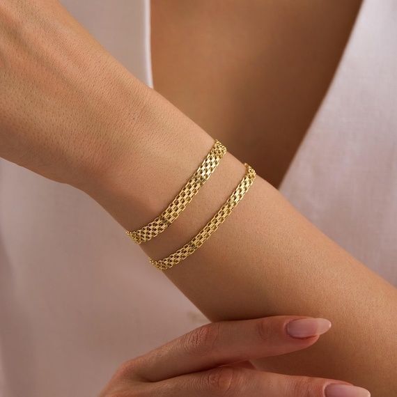Närbild av handled med två guldfärgade Bismarck-armband
